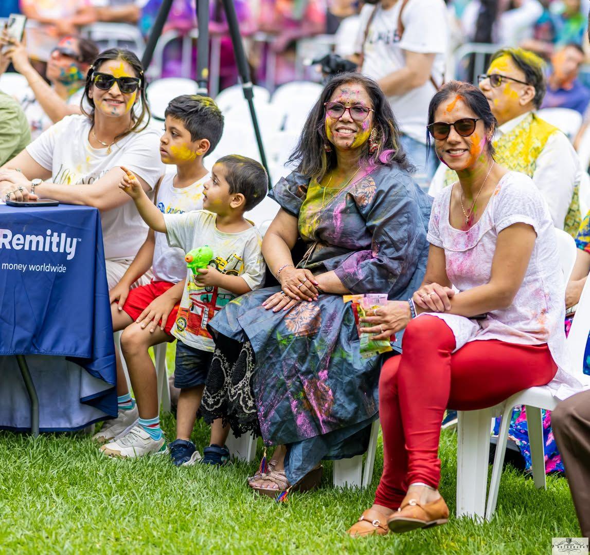 A family watching the stage, covered head to toe in colour